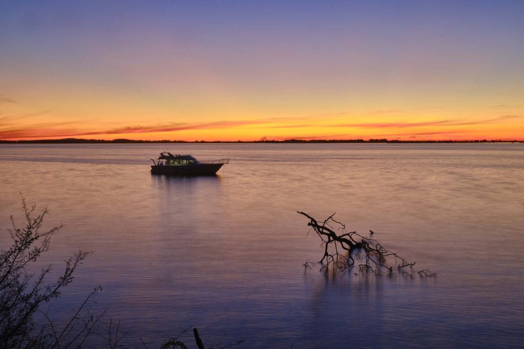 Sailing boat on the calm beautiful ocean with the breathtaking sunset